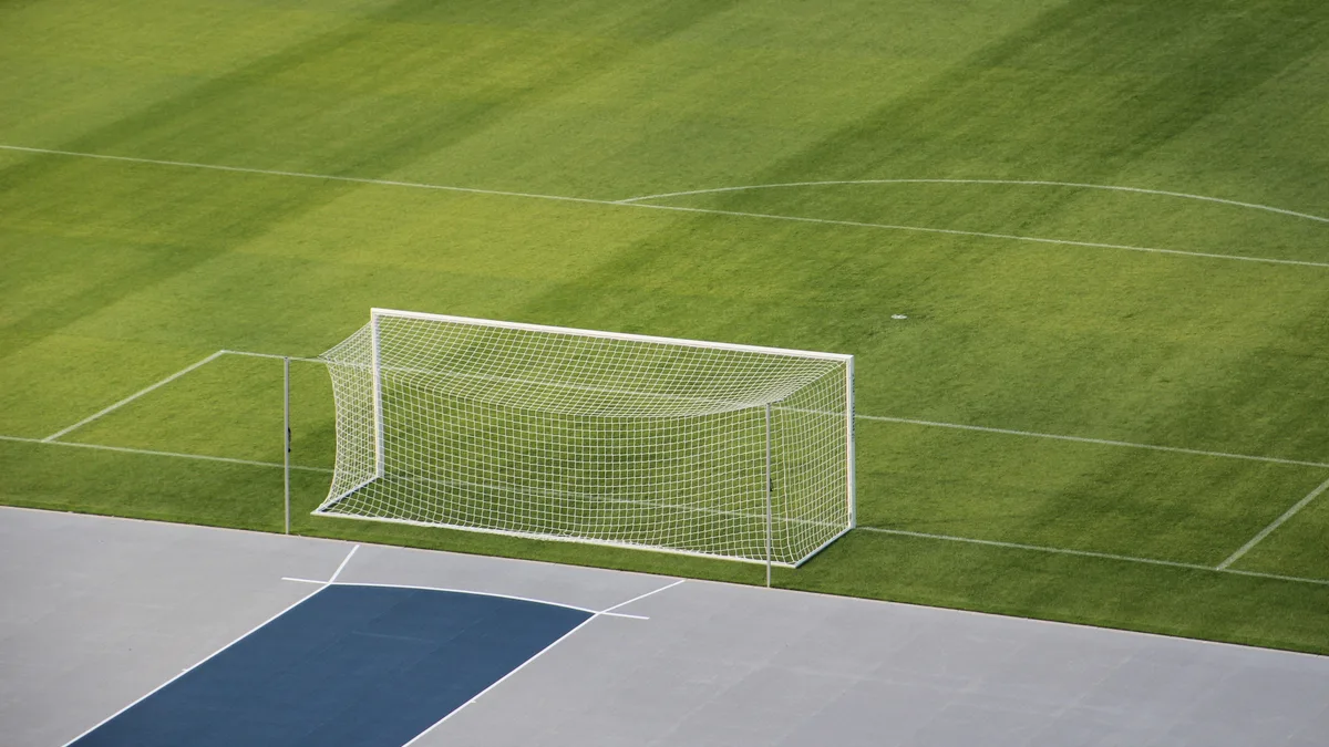 Campo de futebol vazio visto de cima, com o gol e a grama bem cuidada