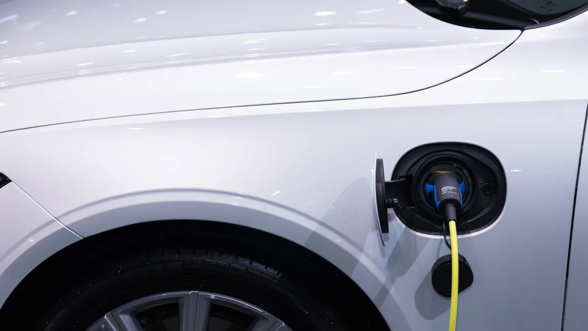 Carro elétrico branco com o cabo de recarga conectado à tomada do veículo