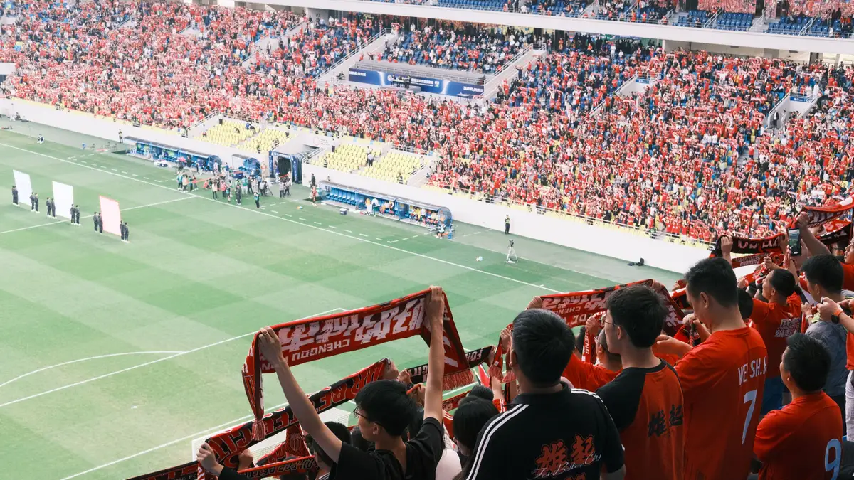 Torcida agitando lenços e torcendo em estádio de futebol lotado