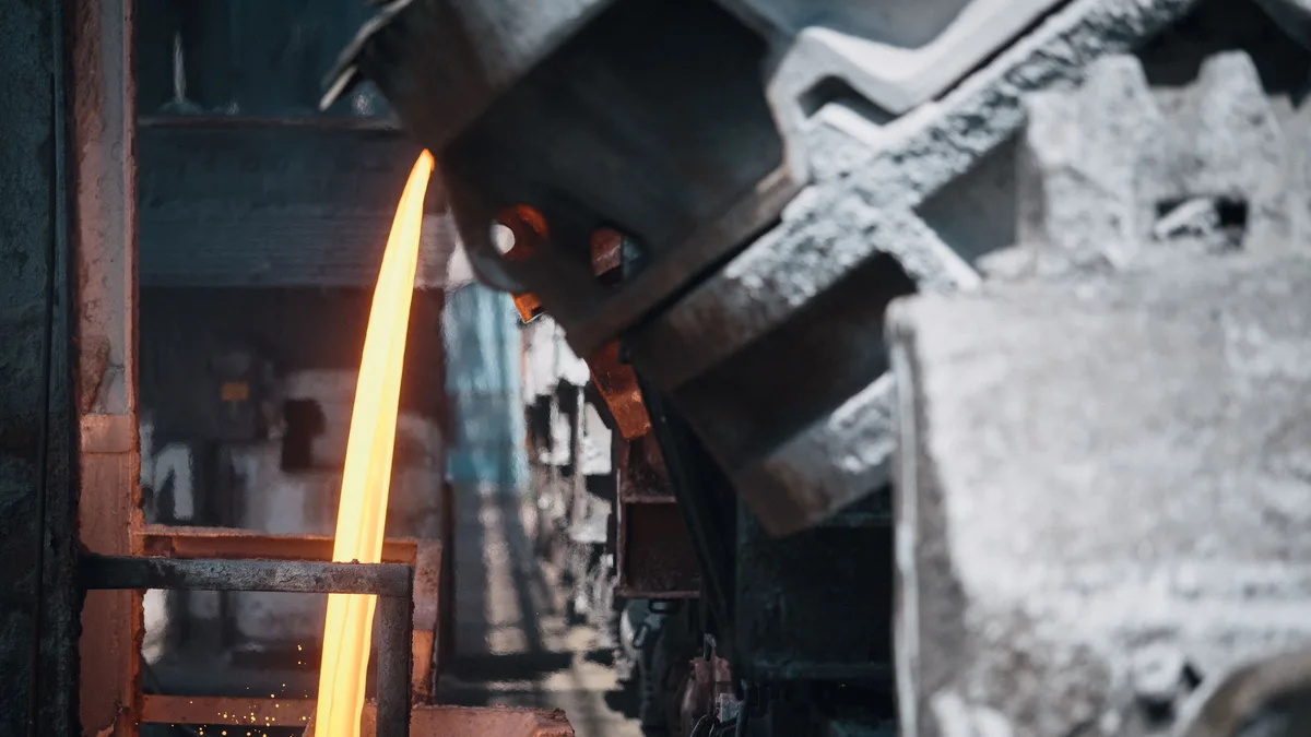 Jato de metal incandescente sendo vazado dentro de uma usina siderúrgica