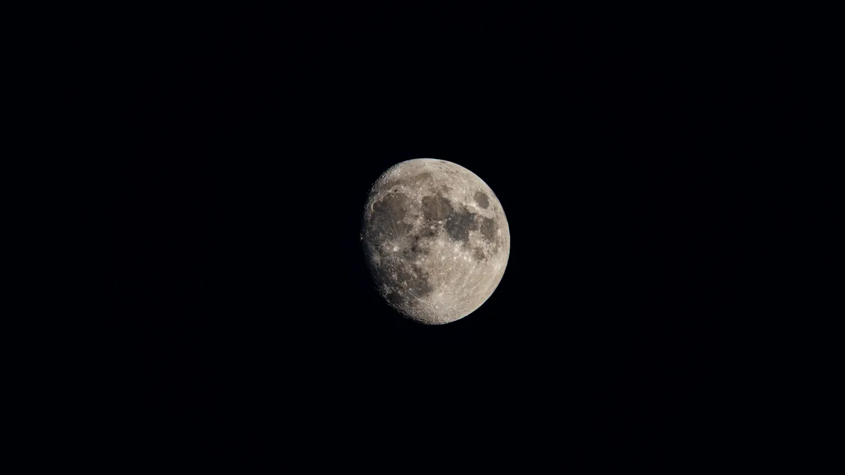 Lua gibosa minguante, com crateras visíveis, em céu noturno escuro