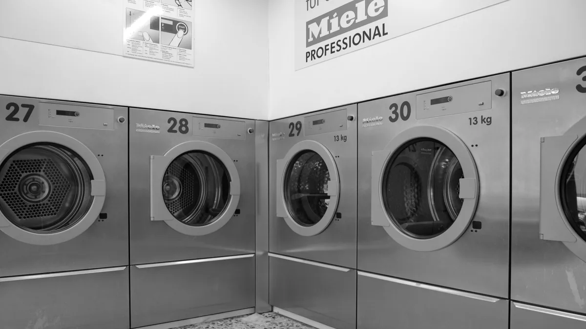 Fileira de máquinas de lavar industriais em lavanderia moderna e organizada