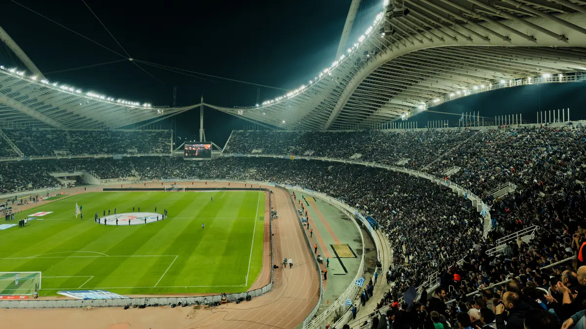 Estádio de futebol lotado sob os refletores durante uma partida noturna