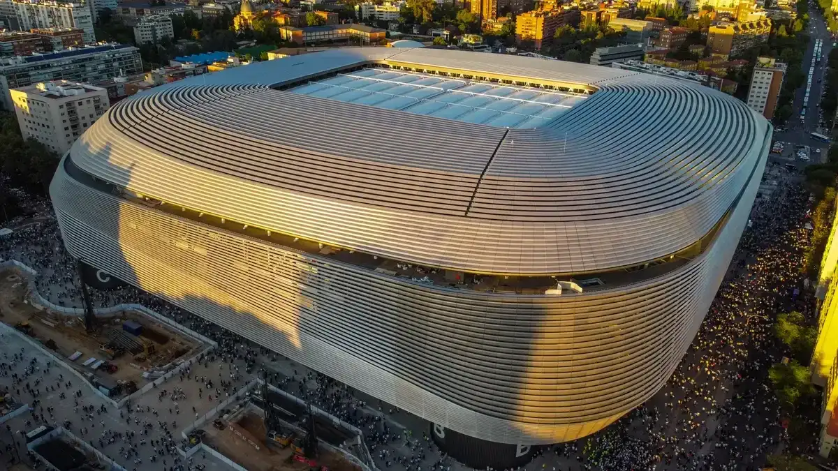Vista aérea de um grande estádio de futebol iluminado ao entardecer