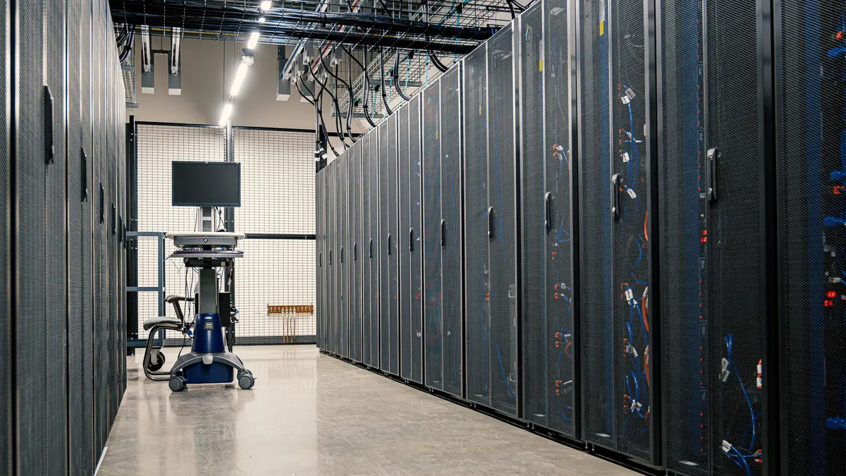 Corredor de data center com fileiras de racks de servidores acesos