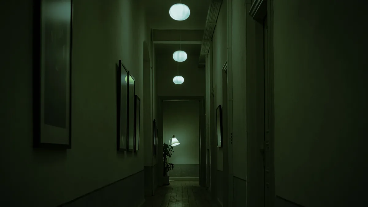 Corredor estreito e vazio, iluminado por luz esverdeada, em clima de suspense