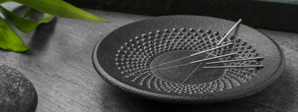 agulhas de acupuntura em um prato preto chinês
